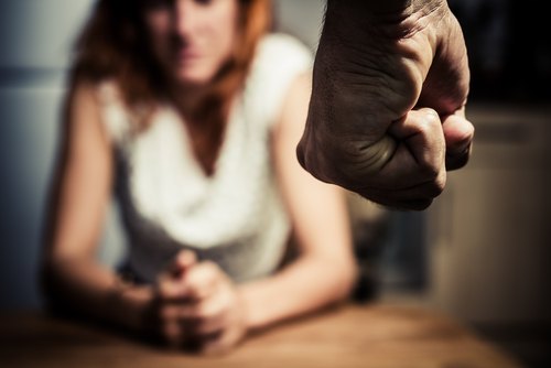 woman sitting down while man is about to attack her