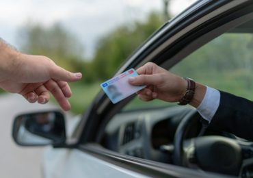 man offering his driver's license to the police after being stopped